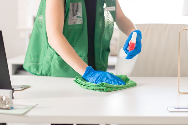 janitor cleaning office desk during daytime