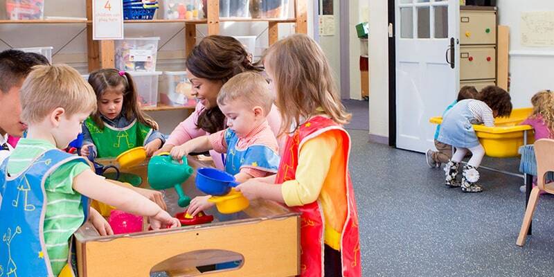 preschool student picking toy tools out of a container while an instructor explains the activity