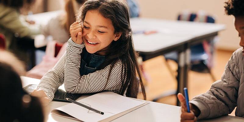 A student reads her book in a clean classroom as planned by a custom cleaning plans for schools