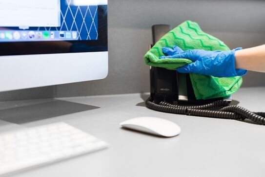 professional commercial cleaning employee wiping down office phone