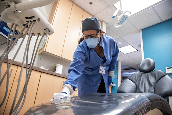 Essential employee cleaning patient chair at Medical facility