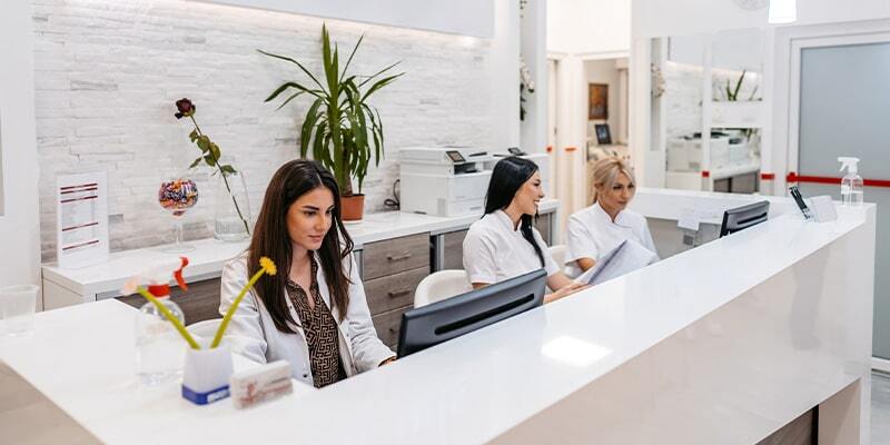 front desk administrators at a dental office prepare to welcome incoming appointments