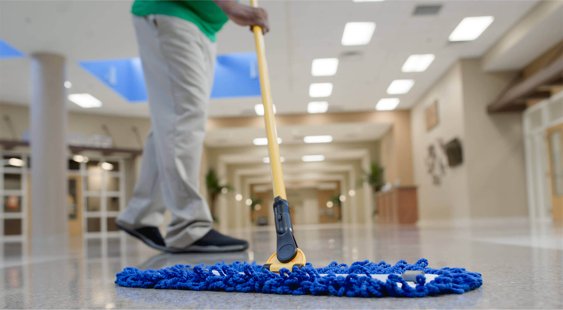 low floor view of a a commercial cleaning professional moping office floors near an entrance