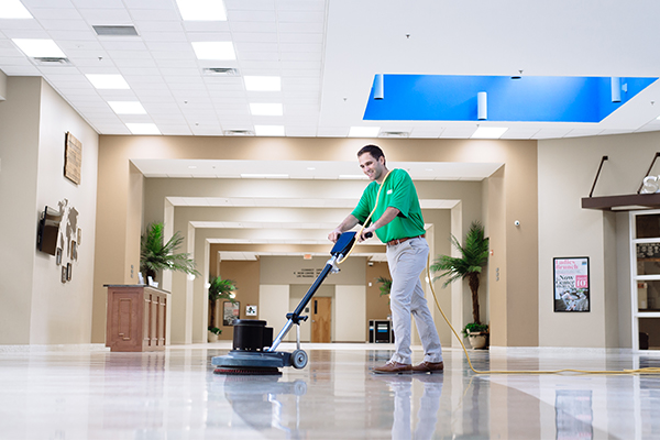 Professional commercial cleaner polishing lobby floor of corporate building