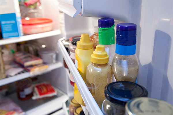 refrigerator door open and full of sauce bottles