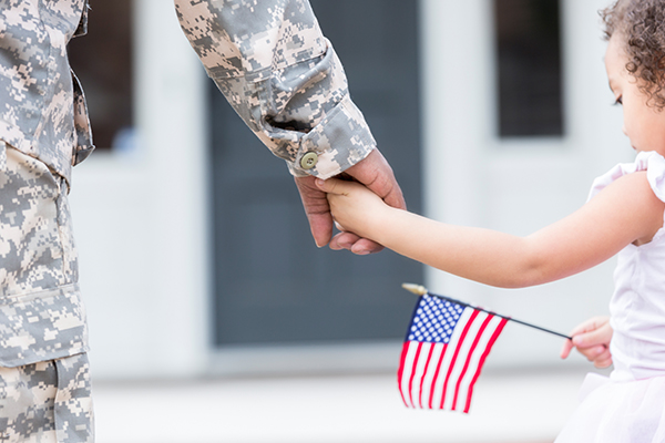 Veteran holding hand of child with American flag in her hand