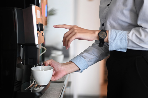 Business professional using their company coffee machine in the office break room.