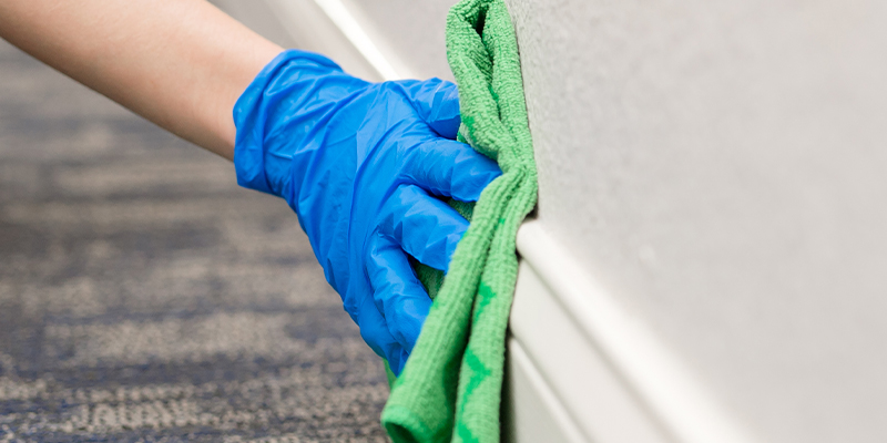 professional cleaner hand with rag cleaning wall area following the checklist