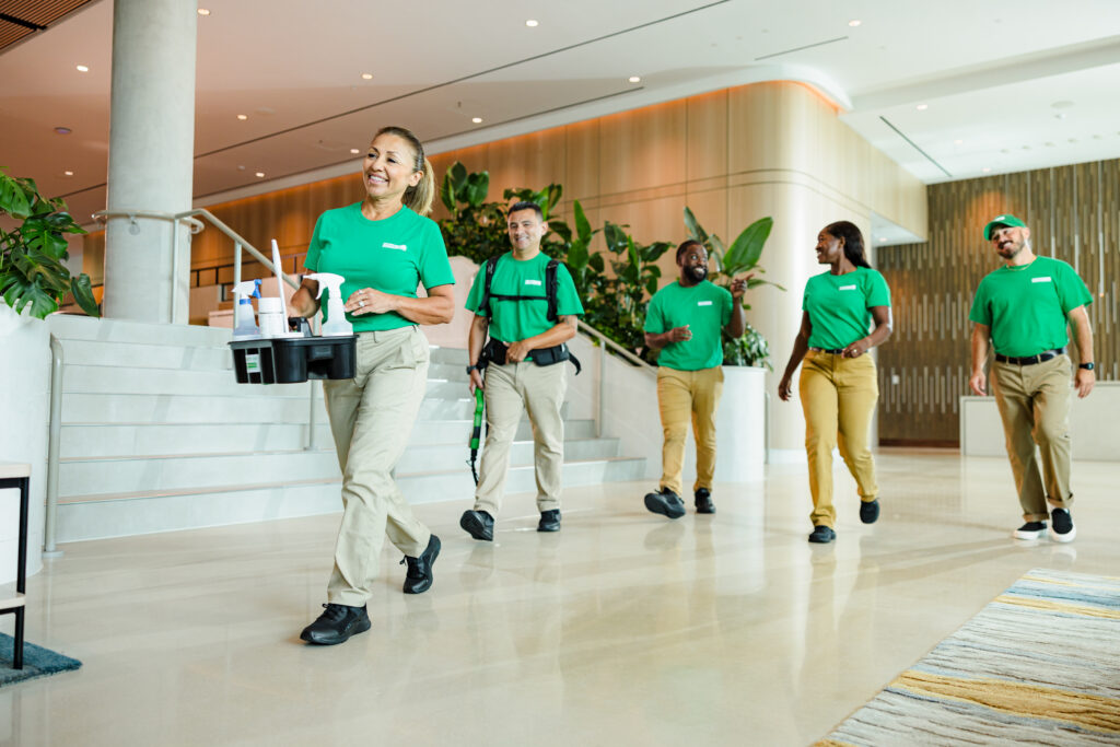 Office Pride cleaning team in green uniforms in a building lobby