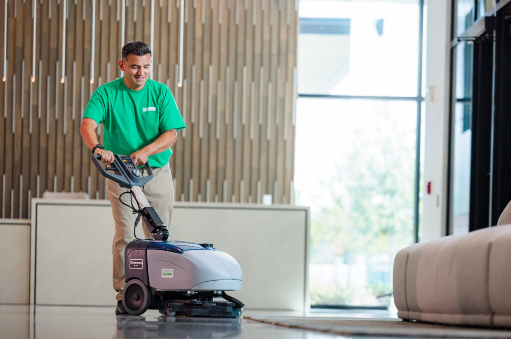 Office Pride technician running an auto-scrubber across a lobby floor