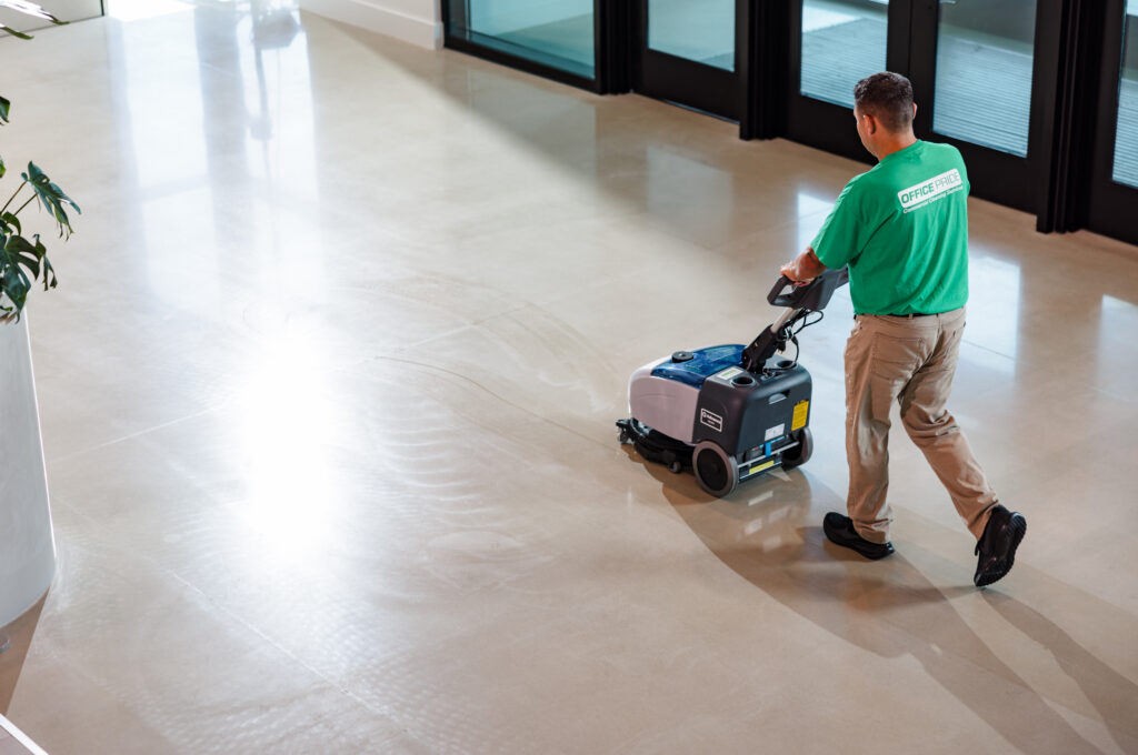 Office Pride team member vacuuming a building lobby during the day