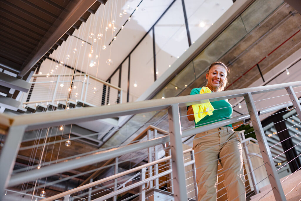 Office Pride cleaner wiping down a glass railing