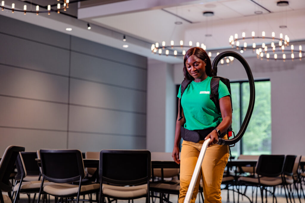 Office Pride cleaner vacuuming a cafeteria with a backpack vacuum